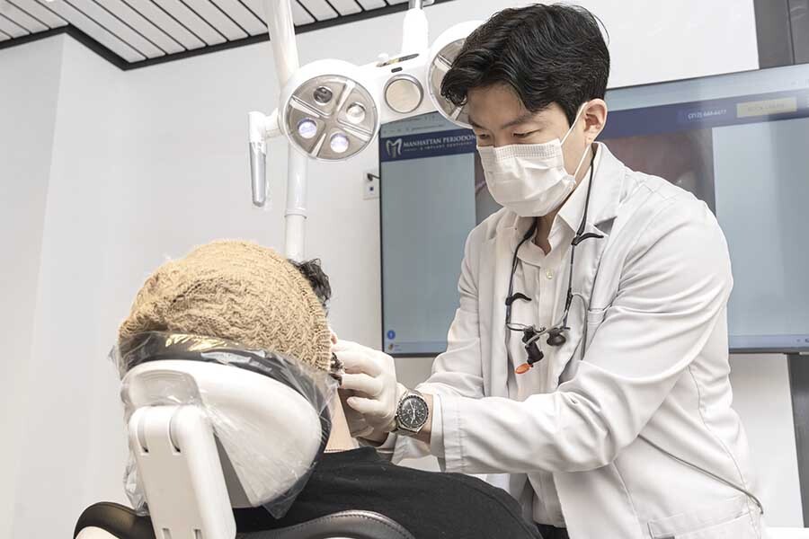 Orthodontist performing metal braces adjustment with brackets and wires during treatment in Midtown Manhattan NYC